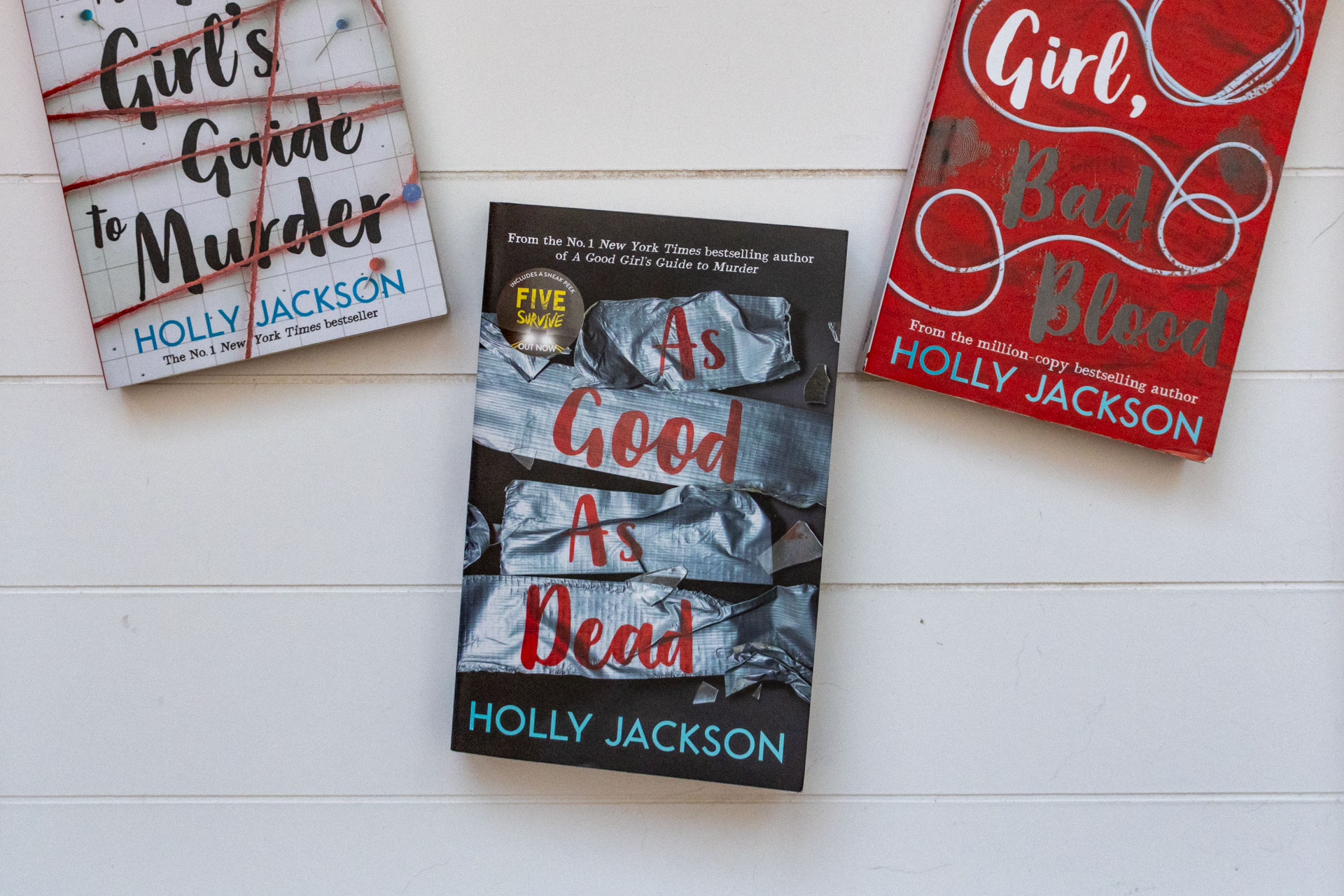 Boek As Good As Dead van Holly Jackson met de A Good Girls's Guide to Murder links half in beeld en Good Girl, Bad Blood rechts half in beeld.