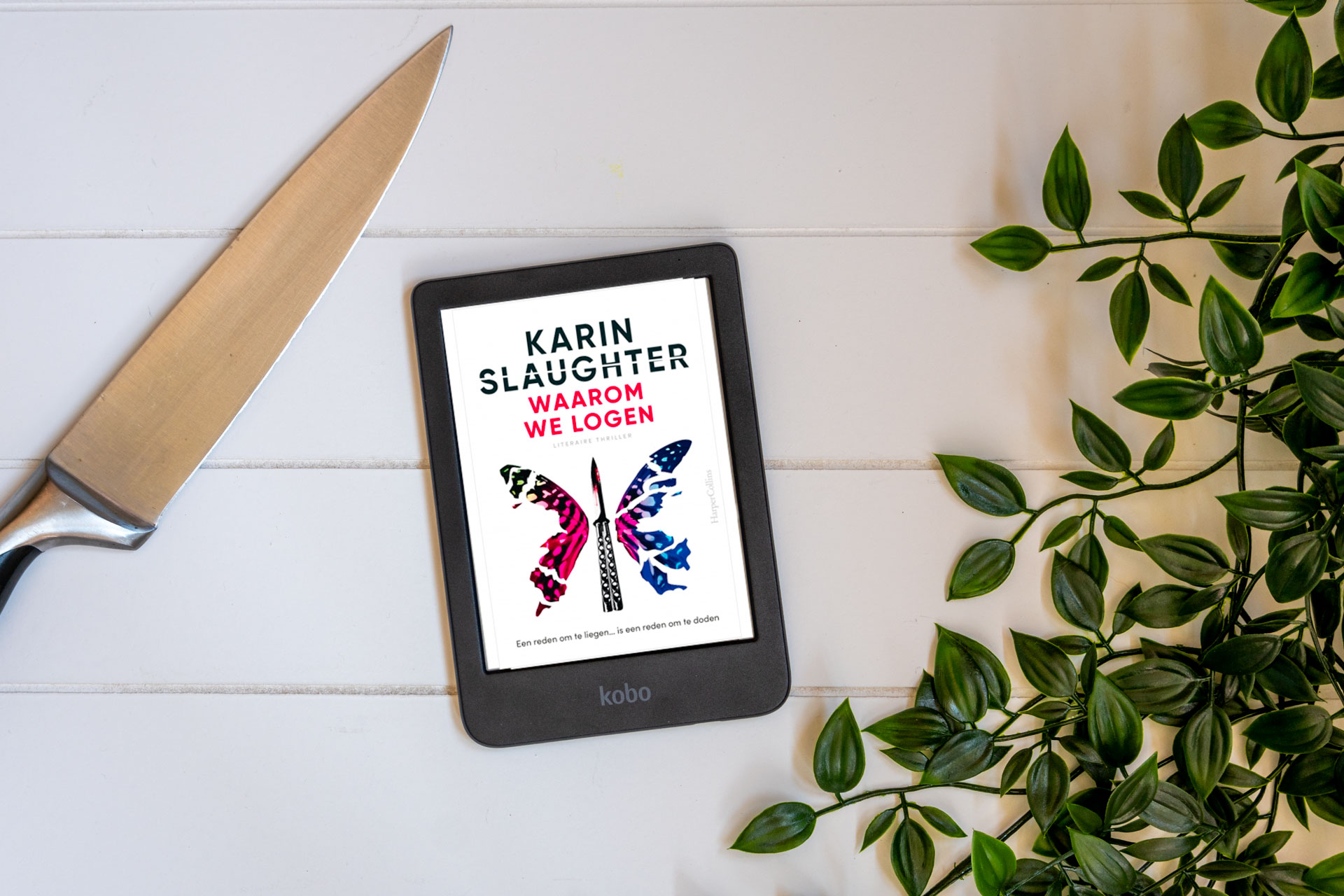 E-reader met cover van Waarom we logen van Karin Slaughter met een mes erbij en wat groen