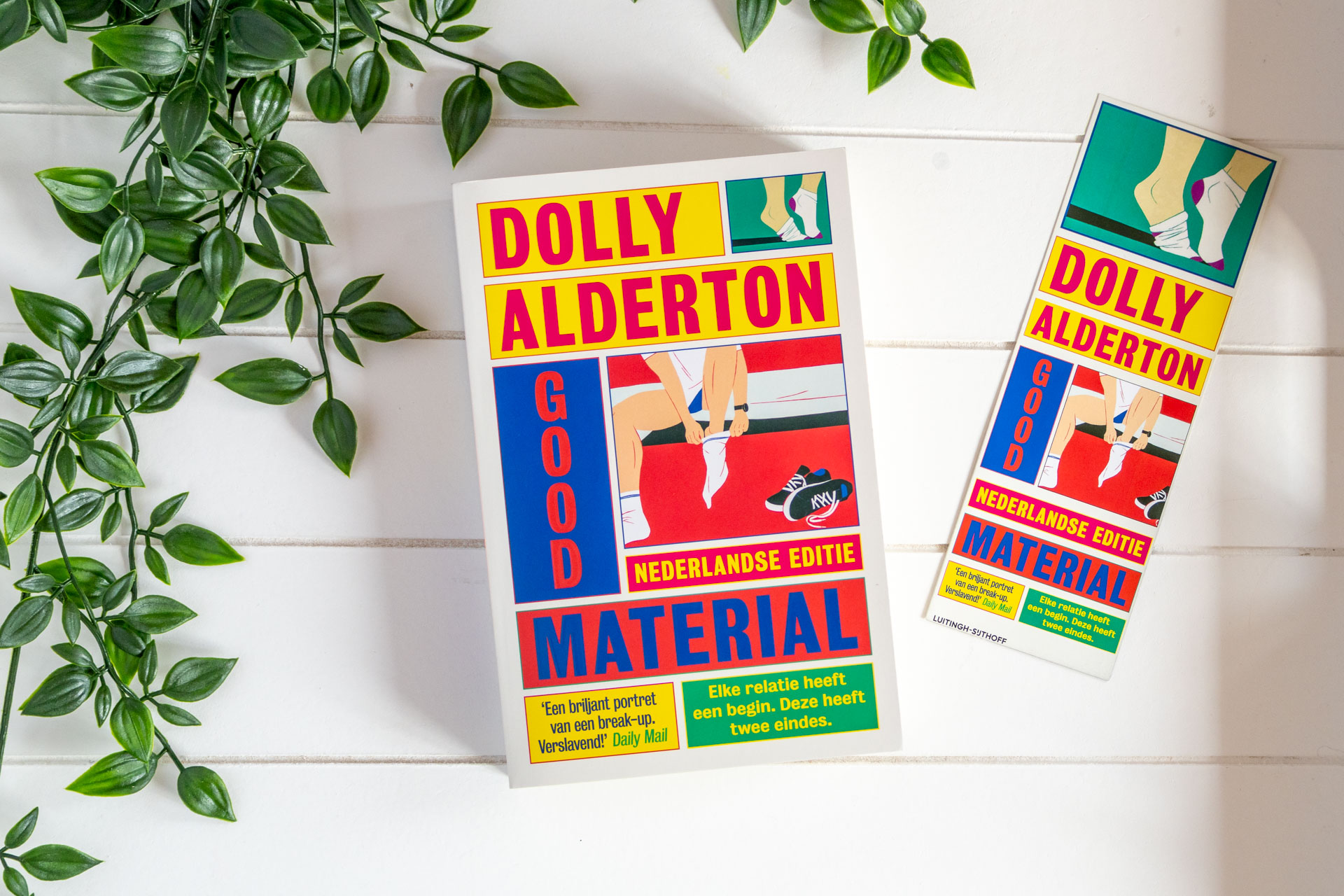 Boekrecensie van Good Material van Dolly Alderton: boek tegen witte achtergrond met groene hangplant eromheen