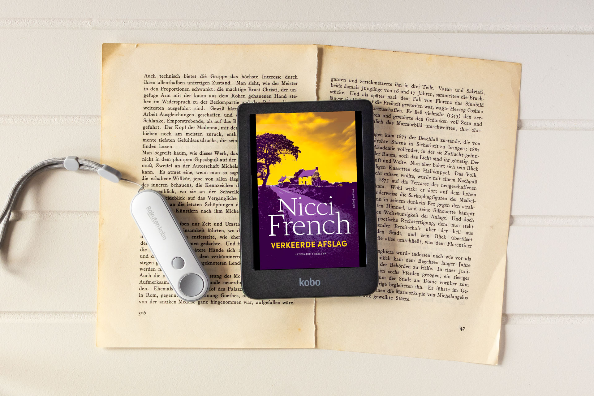 Het e-book Verkeerde afslag van Nicci French staat op een Kobo e-reader die op opengeslagen, vergeelde boekpagina’s ligt. Op het scherm zie je een contrastrijke cover met een huis en boom tegen een geel-paarse lucht, met de titel Verkeerde afslag en de auteursnaam duidelijk leesbaar. Links naast de e-reader ligt een witte afstandsbediening met koord.